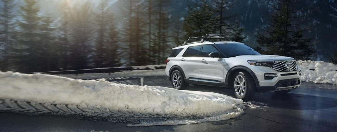 A white 2022 Ford Explorer is shown rounding a snowy corner after leaving a Ford dealership near Cohoe.