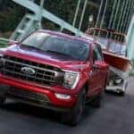 One of the more popular used trucks for sale near Schenectady, a red 2021 Ford F-150, is shown driving on a bridge.