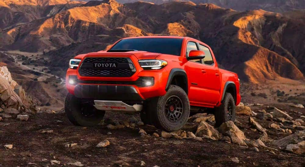 A red 2023 Toyota Tacoma TRD Pro is shown driving on a rocky hill.