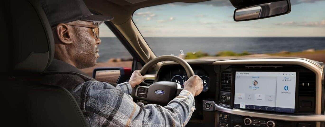 A man is shown driving a 2024 Ford F-150 during a 2024 Ford F-150 vs 2024 Chevy Silverado 1500 comparison.