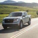 A grey 2022 Ford Maverick is shown driving on an open road after looking at used trucks for sale near Colonie.