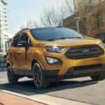 A gold 2022 Ford EcoSport is shown driving on a city street to view used SUVs for sale near Schenectady.