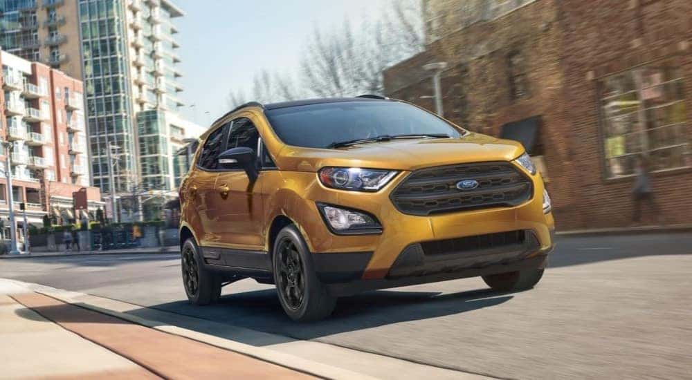 A gold 2022 Ford EcoSport is shown driving on a city street to view used SUVs for sale near Schenectady.
