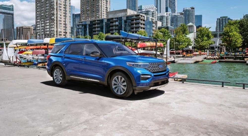 A blue 2023 Ford Explorer Limited is shown driving near a city.