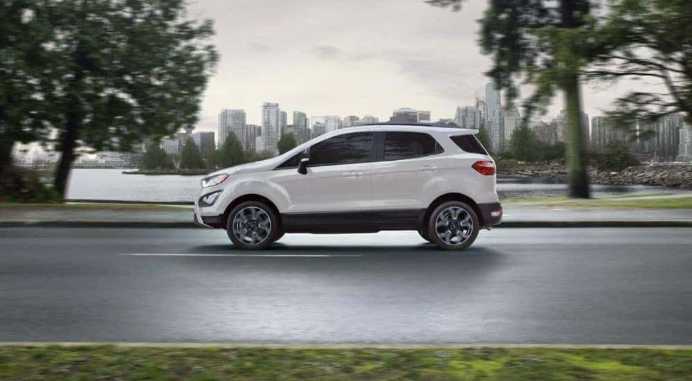 A white 2020 Ford EcoSport is shown driving near a city.