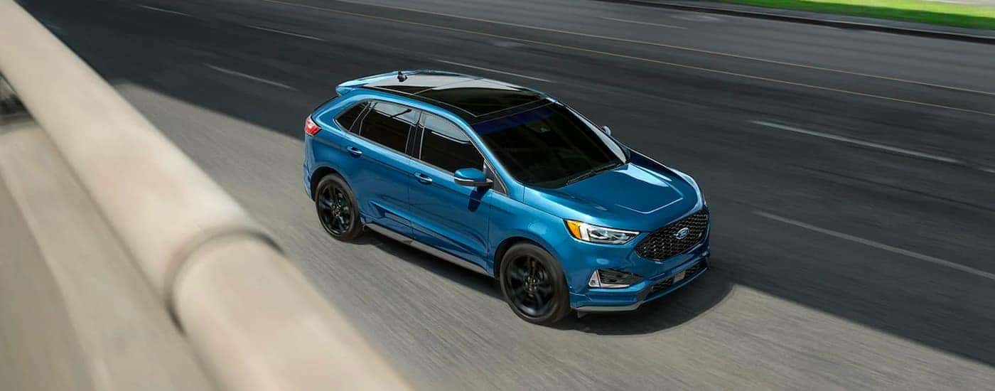 A blue 2020 Ford Edge ST is shown driving on a city street.
