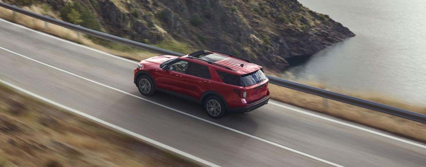 A red 2021 Ford Explorer is shown driving near an ocean.