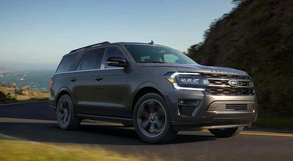 One of many popular used SUVs for sale near Colonie, a gray 2022 Ford Expedition Stealth Performance Edition, is shown driving on a highway.