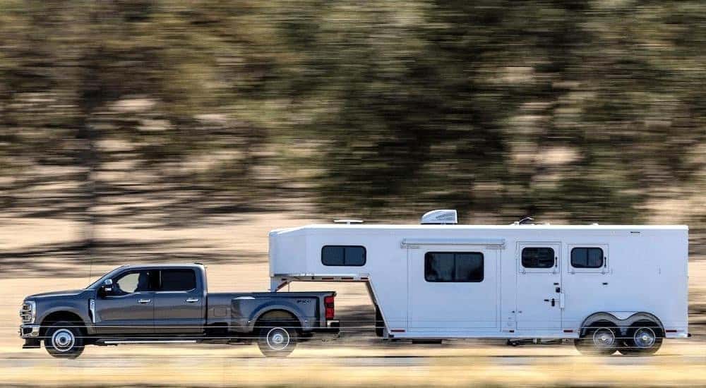 A grey 2024 Ford F-350 Lariat is shown towing a trailer.