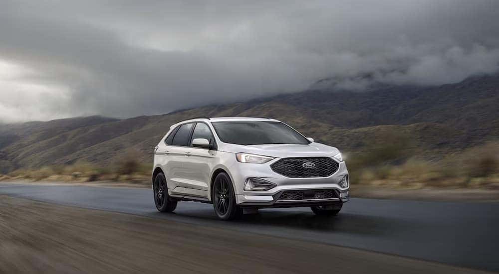 A white 2023 Ford Edge is shown driving on a cloudy road.