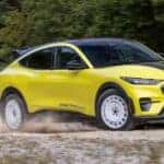 A yellow 2024 Ford Mustang Mach-E Rally Edition is shown driving away from a Ford EV dealership in Hudson Valley, NY.