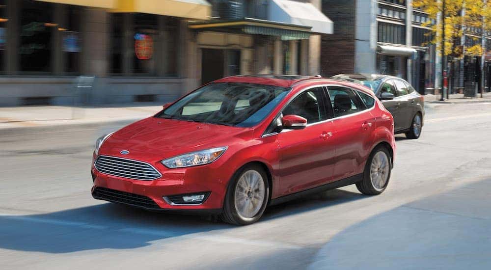 A red 2016 Ford Focus is shown driving in a town.