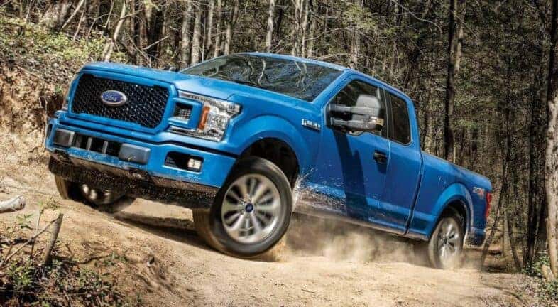 A blue 2019 Ford F-150 is shown driving off-road after visiting a used Ford dealership near Halfmoon.