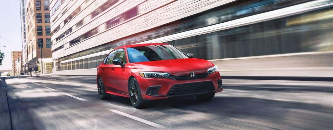 A red 2022 Honda Civic Touring is shown driving on a city street.