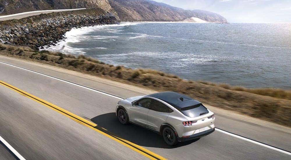 A white 2024 Ford Mustang Mach-E is shown driving.