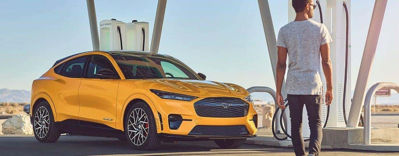 A yellow 2024 Ford Mustang Mach-E is shown charging.