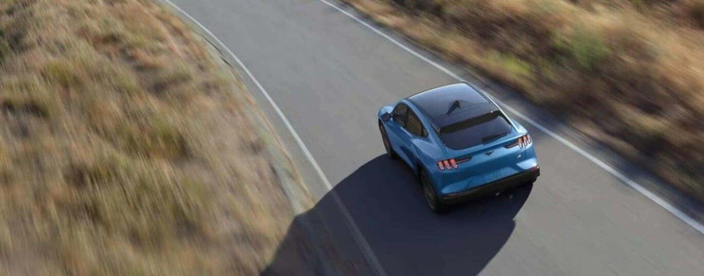 A blue 2024 Ford Mustang Mach-E is shown from a high angle while driving.