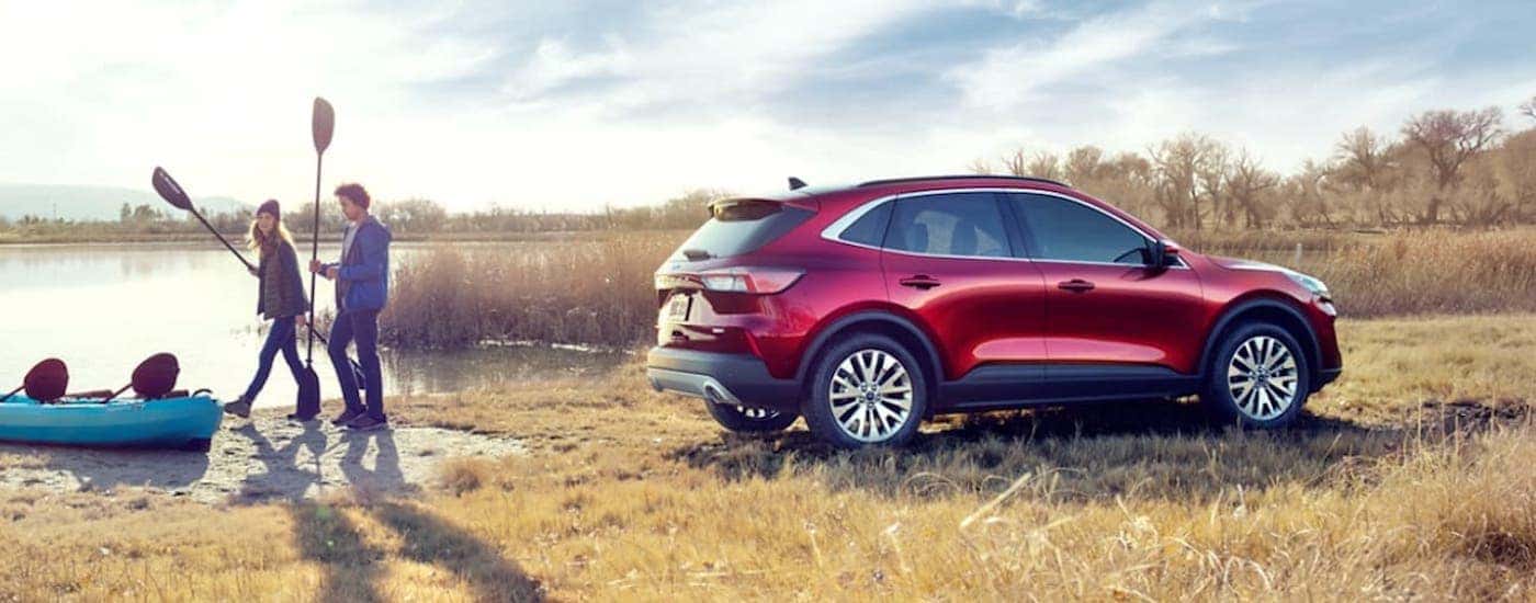 Two people are shown walking away from a parked red 2020 Ford Escape parked by a lake.