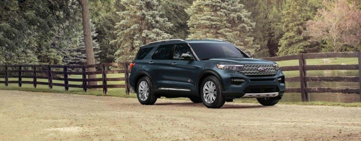 A blue 2024 Ford Explorer King Ranch is shown driving near a fance after a 2024 Ford Explorer vs 2024 Honda Pilot comparison.