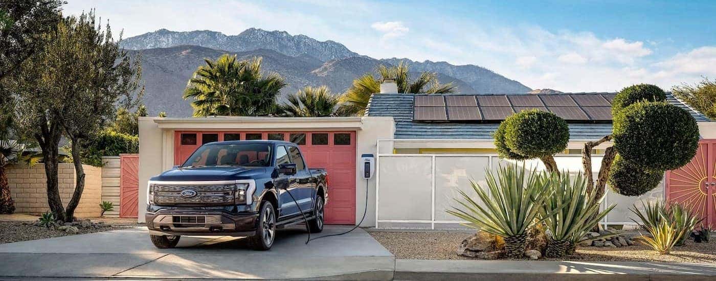 A blue 2023 Ford F-150 Lightning is shown charging after visiting a NY Ford EV dealer.