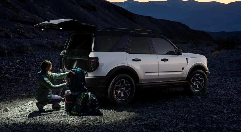 People are shown loading cargo into the open hatchback of a white 2024 Ford Bronco Sport Big Bend