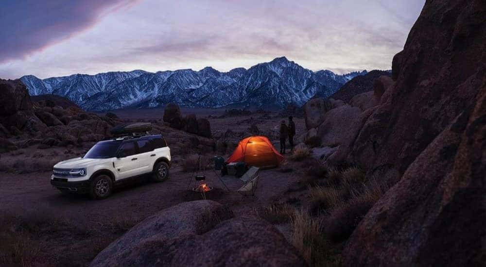 A white 2024 Ford Bronco Sport is shown parked at a campsite after a 2024 Ford Bronco Sport vs 2024 Dodge Hornet comparison.