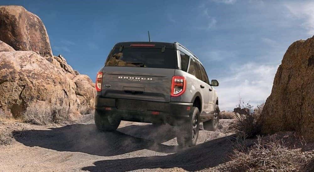 A tan 2024 Ford Bronco Sport is shown from a rear angle while driving off-road.