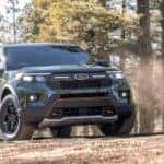 A dark green 2024 Ford Explorer Timberline is shown driving in a forest after a 2024 Ford Explorer vs 2024 Honda Pilot comparison.