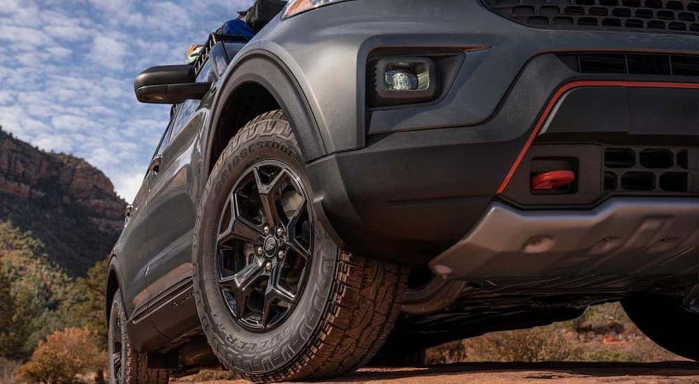 The front wheel of a grey 2024 Ford Explorer Timberline is shown at a low angle.