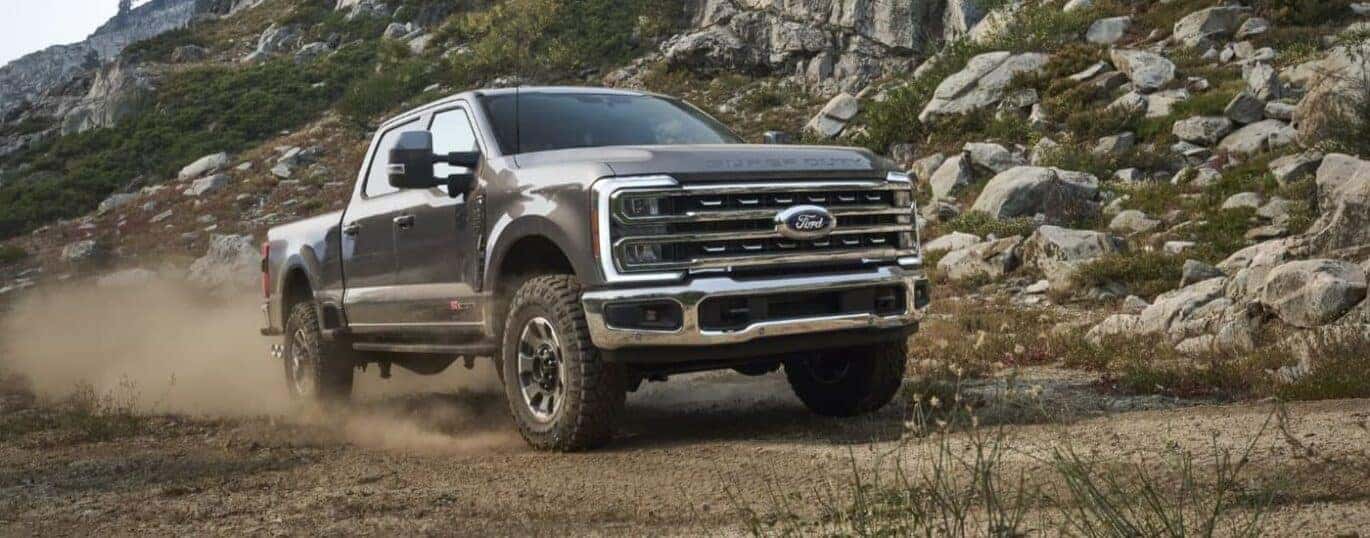 A black 2024 Ford F-250 Tremor is shown driving on a dusty road after a 2024 Ford Super Duty vs 2024 Chevy Silverado HD comparison.