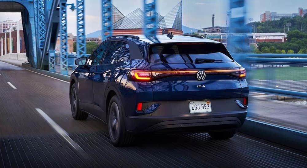 A blue 2024 Volkswagen ID.4 driving on a city bridge.