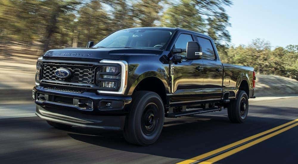 A black 2024 Ford Super Duty F-250 driving on an open road.