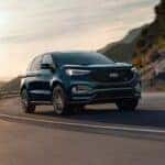 A blue 2023 Ford Edge ST driving on a mountain highway.