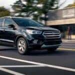 A black 2019 Ford Escape is shown driving in a city after visiting a dealer with a used Ford Escape for sale.