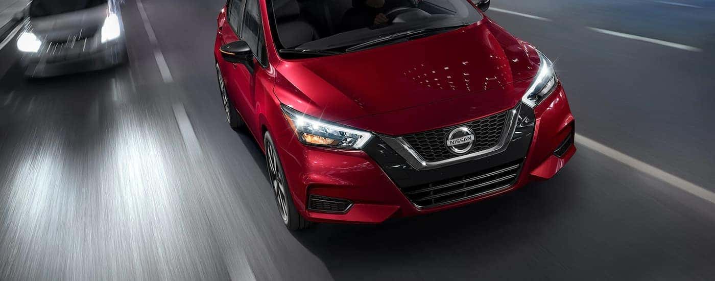 Red 2022 Nissan Versa driving on a highway at night