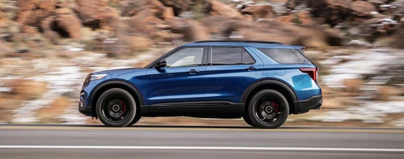 A blue 2024 Ford Explorer is shown from the side against a blurred background.