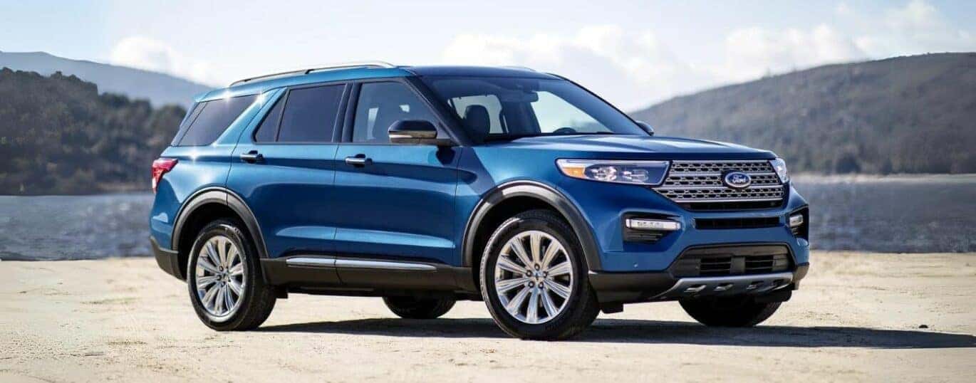 A blue 2024 Ford Explorer is shown in front of a lake.