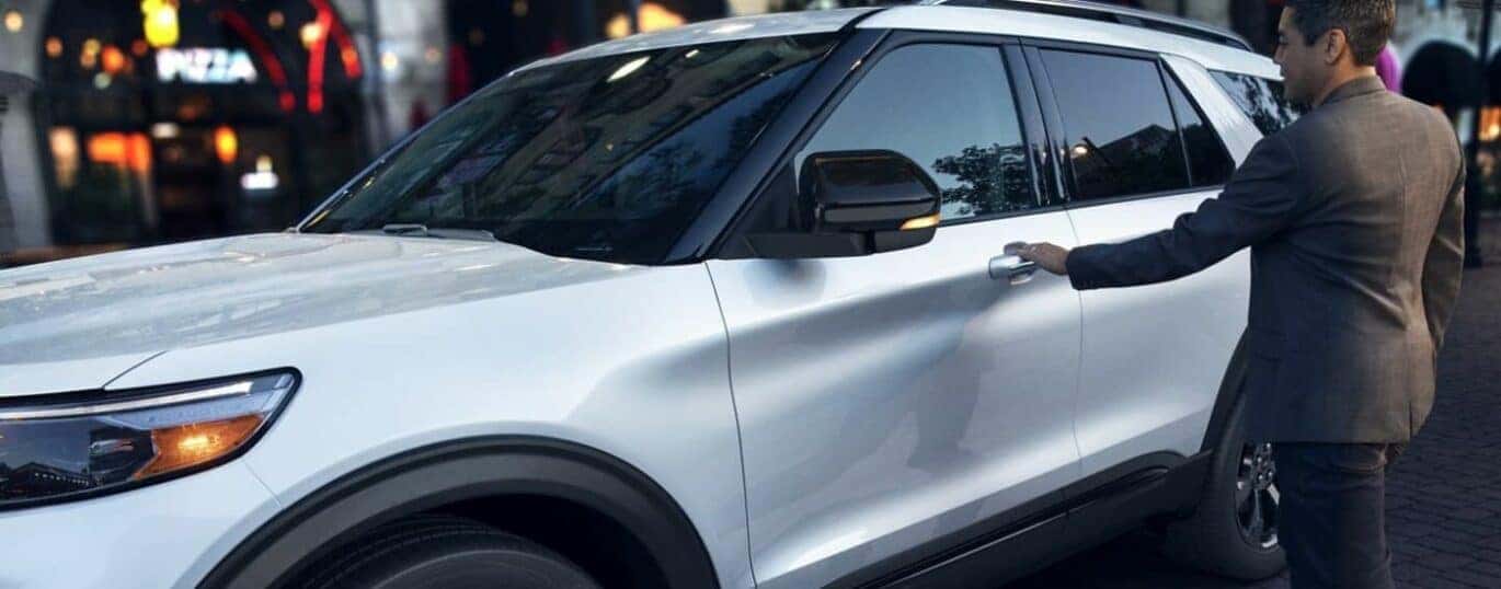 A person is shown opening the door on a white 2024 Ford Explorer ST.