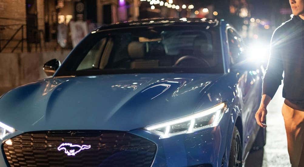 A blue 2024 Ford Mustang Mach-E is shown parked at night.