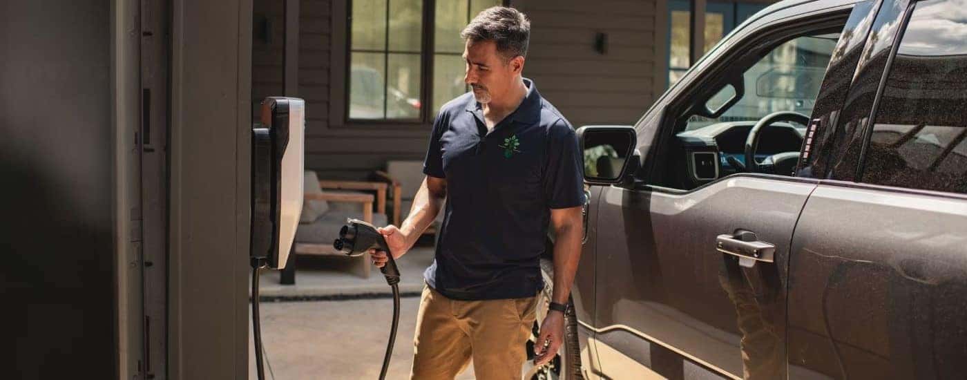 A man is shown plugging in a brown 2024 Ford F-150 Lightning to a charging port.