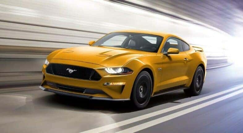 A yellow 2022 Ford Mustang, one of many used cars for sale near Schenectady, driving through a tunnel.