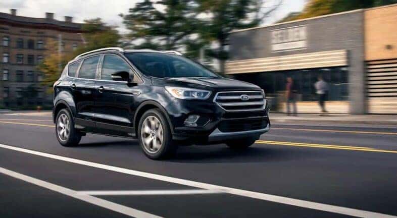 A black 2019 Ford Escape driving on a city street after viewing used SUVs for sale near Delmar.