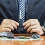 A salesman is shown holding a key after selling used SUVs for sale.