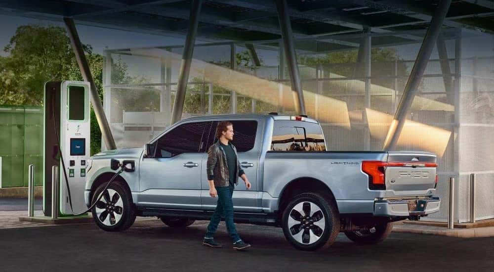A light blue 2024 Ford F-150 Lightning is shown charging.