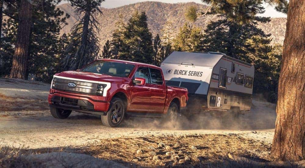 A red 2024 Ford F-150 Lightning is shown towing a trailer.