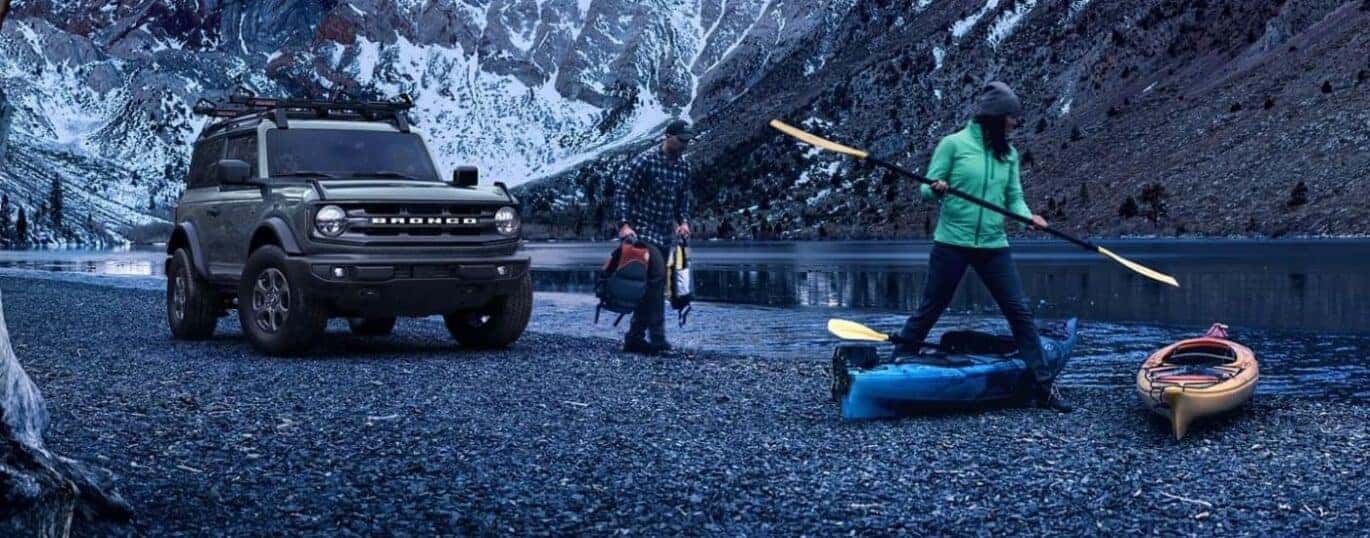 A grey 2024 Ford Bronco Big Bend parked off-road by a river.