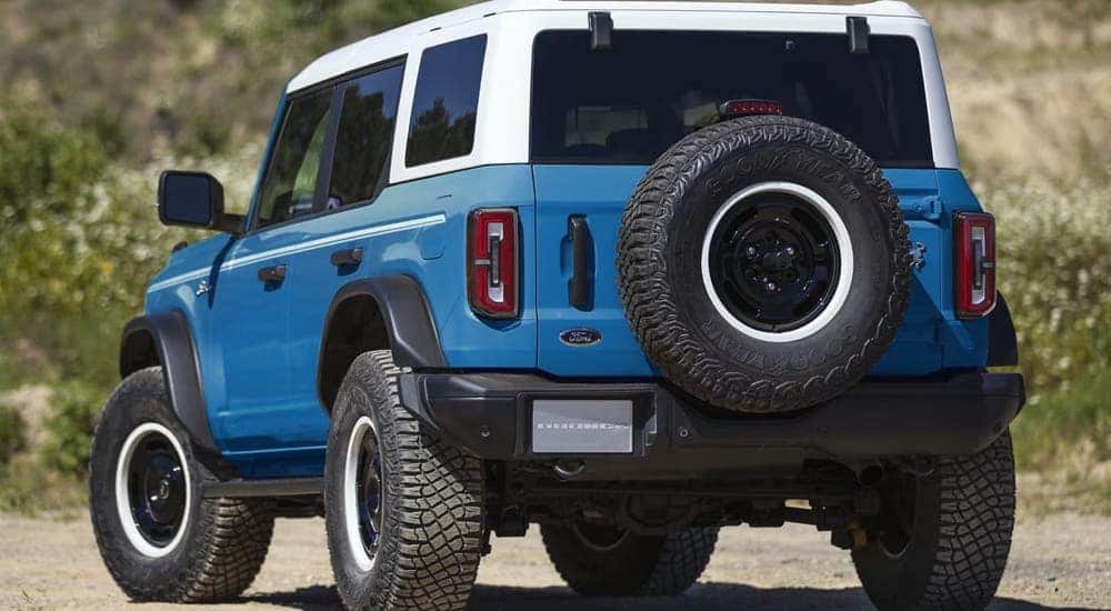 A blue 2024 Ford Bronco Heritage Limited parked on dirt.