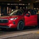 People exiting a red 2024 Ford Escape ST Line Elite parked by a curb.