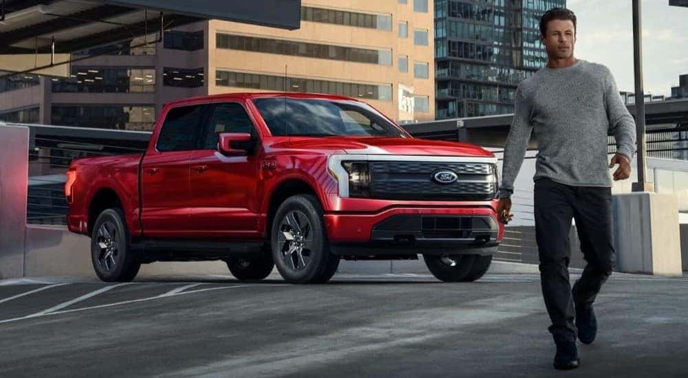 A red 2024 Ford F-150 Lightning for sale is shown parked near a person walking.