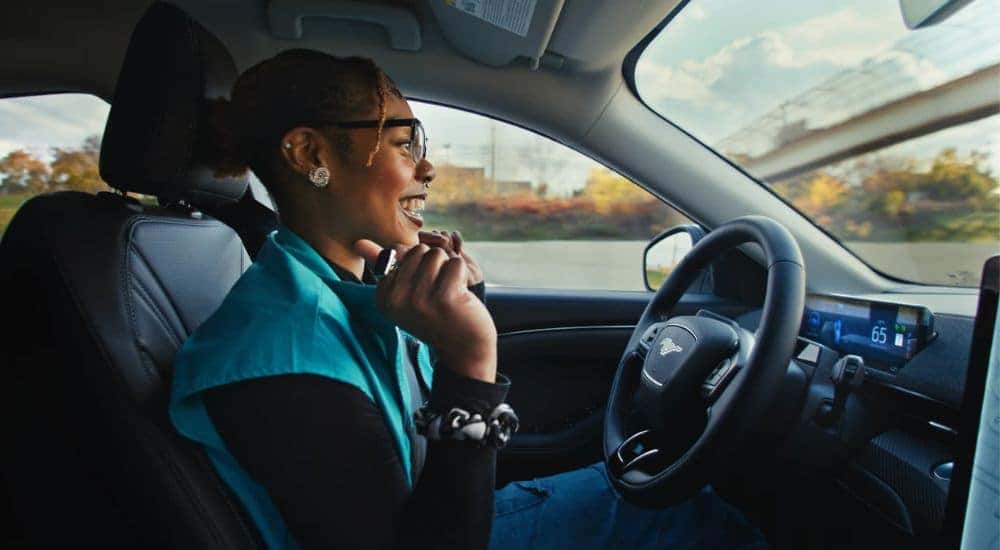 A smiling person is shown in a 2024 Ford Mustang Mach-E.